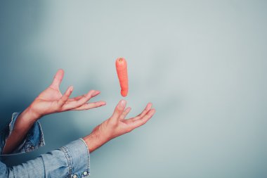 Young man making a carrot levitate clipart