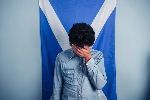 Hombre deprimido de pie frente a la bandera escocesa —  Fotos de Stock