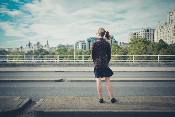 Jonge vrouw permanent op brug in de stad — Stockfoto