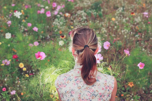 Jeune femme assise dans la prairie — Photo