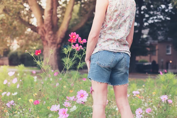 Junge Frau pflückt Blumen auf Wiese — Stockfoto