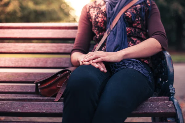 Young woman sitting on park bench — Stock Photo, Image