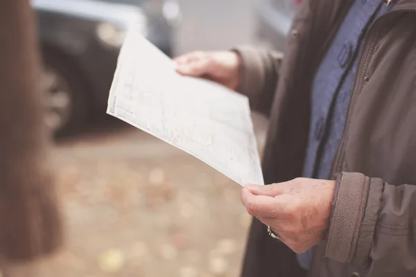 Oude vrouw lezen kaart in de straat — Stockfoto