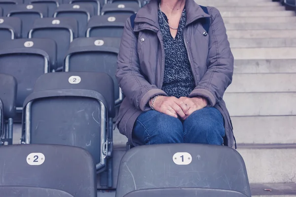 Ältere Frau sitzt auf Tribüne im leeren Stadion — Stockfoto