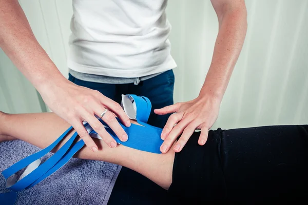 Fisioterapeuta aplicando cinta de cinesio — Foto de Stock