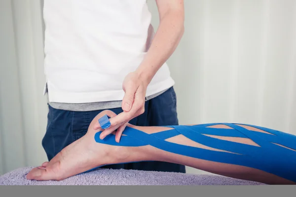 Physiotherapist applying kinesio tape — Stock Photo, Image