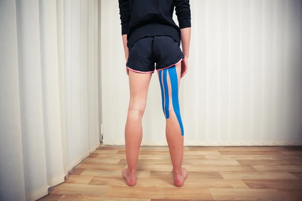 Jonge vrouw met kinesio tape op haar been — Stockfoto
