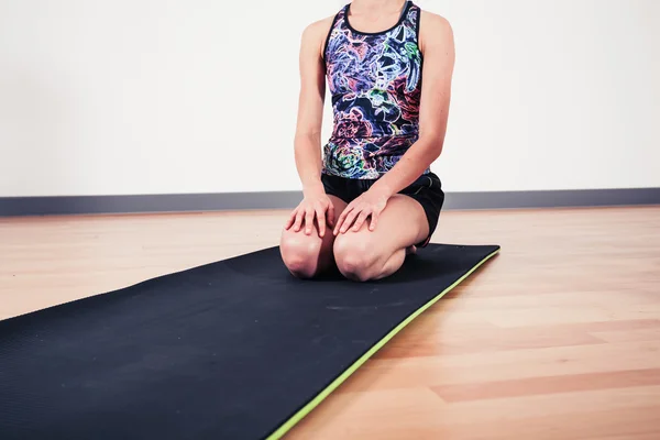 Frau sitzt auf Yogamatte — Stockfoto