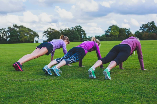 Three women doing push ups in park — Stock Photo, Image