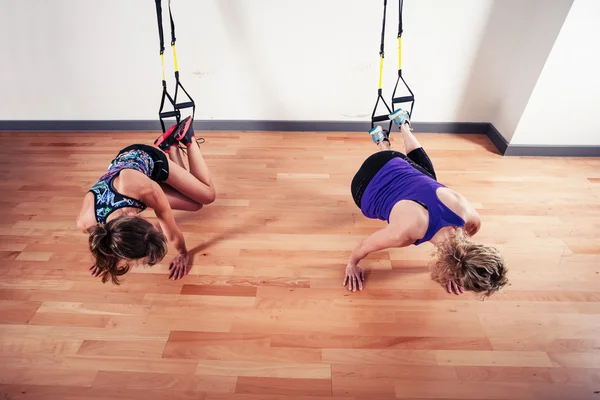 Dos mujeres haciendo ejercicio con correas en el gimnasio —  Fotos de Stock