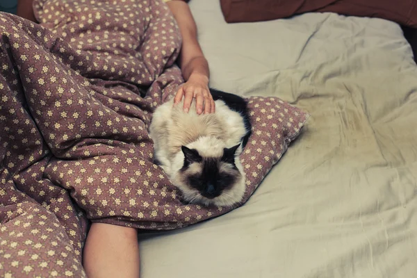 Vrouw en kat in bed — Stockfoto