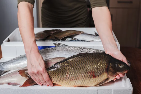 Mulher com uma caixa de peixe em sua cozinha — Fotografia de Stock