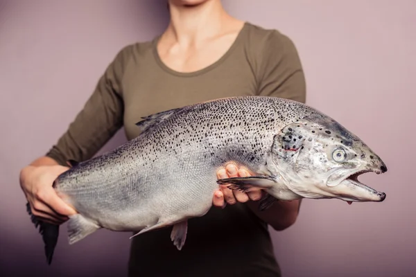 Mujer joven sosteniendo un gran salmón — Foto de Stock