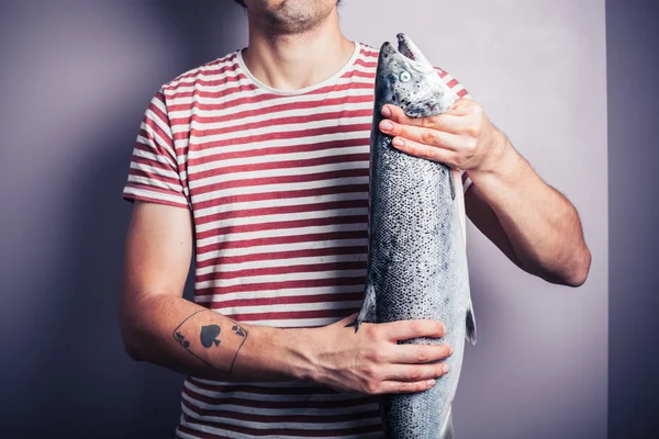 Молодий чоловік позує з лососем — стокове фото