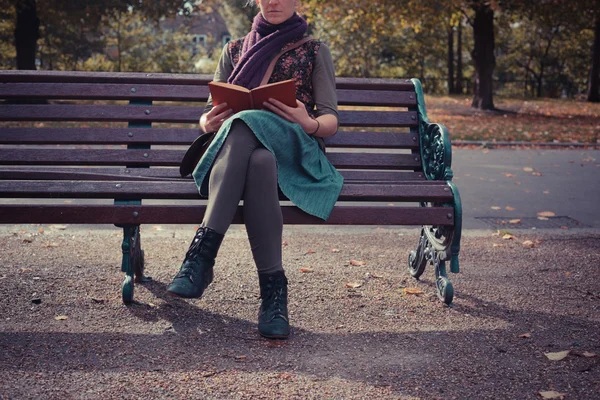 Junge Frau sitzt mit Buch auf Parkbank — Stockfoto