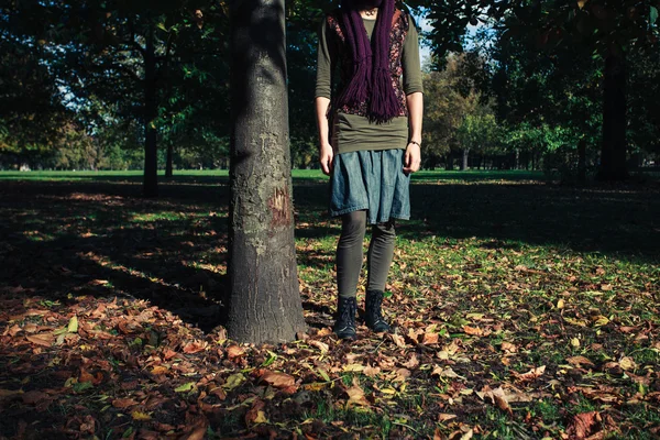 Jonge vrouw permanent door een boom in de herfst — Stockfoto