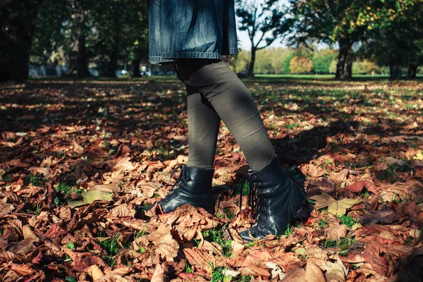 Las piernas de una mujer caminando en hojas caídas — Foto de Stock