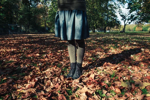 Young woman standing in leaves — Stock Photo, Image