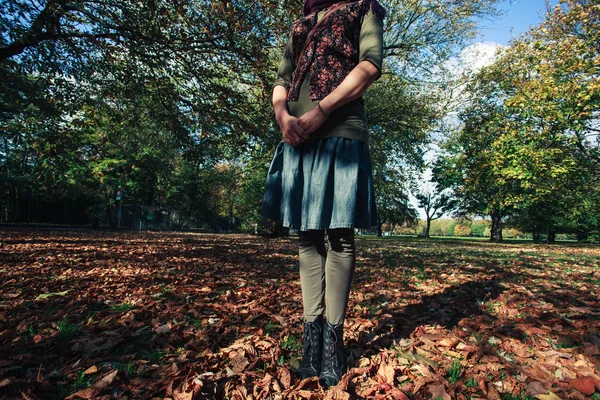 Jonge vrouw permanent in bladeren — Stockfoto