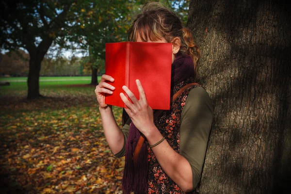 Mulher escondida atrás do livro no parque — Fotografia de Stock
