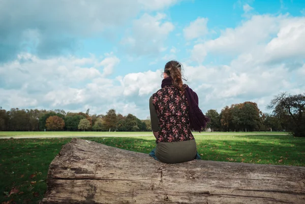 Vrouw zitten op een omgevallen boom in het park — Stockfoto