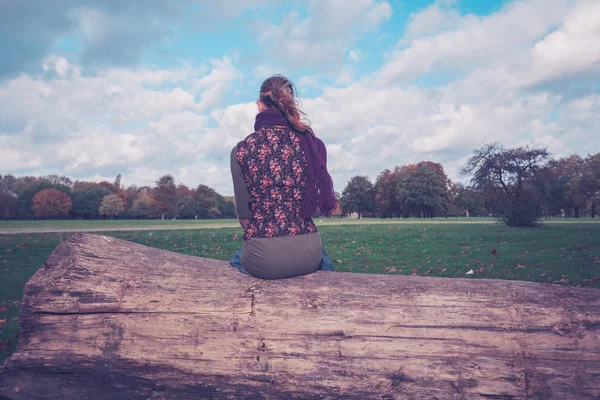 Frau sitzt auf einem umgestürzten Baum im Park — Stockfoto