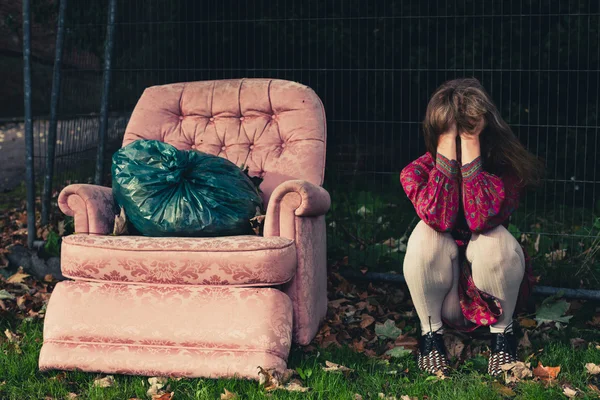 Mujer triste sentada al lado de un sillón afuera — Foto de Stock