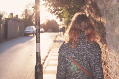 Şehirde gün batımına doğru yürüyen genç kadın