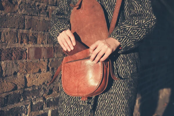 Женщина на закате получает бумажник из сумки — стоковое фото
