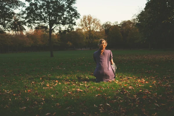 Vrouw zitten op het gras in de avond — Stockfoto