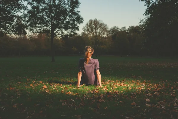 Vrouw zitten op het gras in de avond — Stockfoto