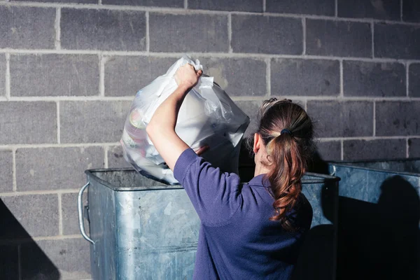 Женщина выбрасывает мусор в мусорку — стоковое фото