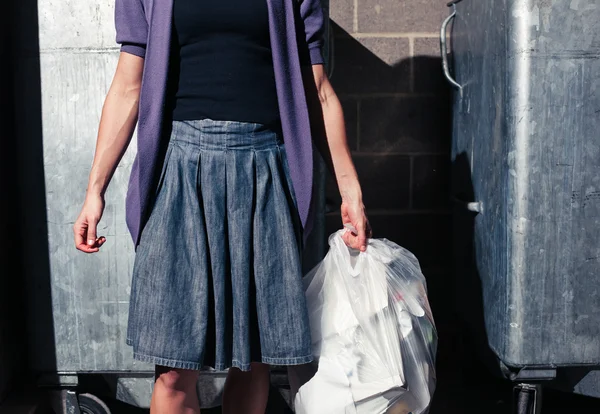 Woman standing next to bins with a bag of rubbish — Stock Photo, Image