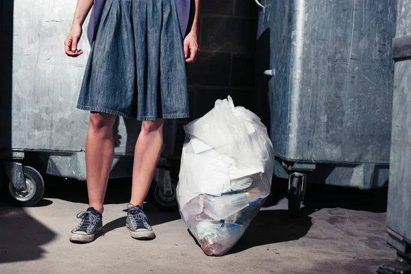 Woman standing next to bins with a bag of rubbish — Stock Photo, Image