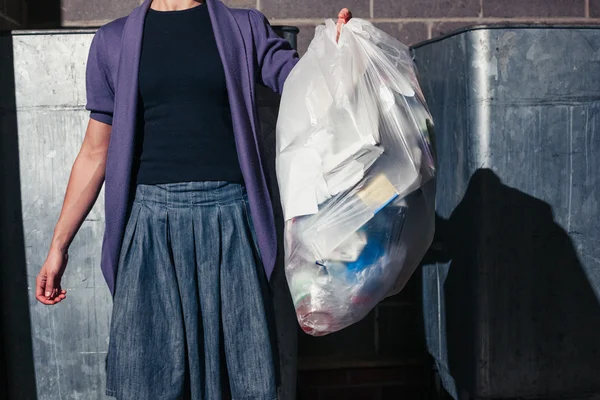 Woman standing next to bins with a bag of rubbish — Stock Photo, Image