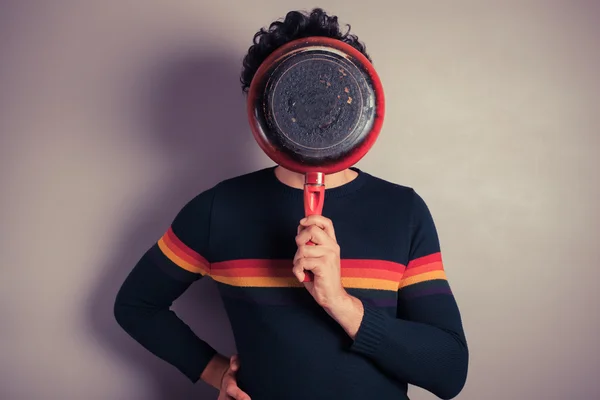 Young man hiding beind frying pan — Stock Photo, Image