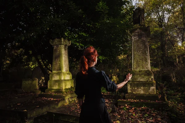 Redhead woman performing ritual at grave — Stock Photo, Image