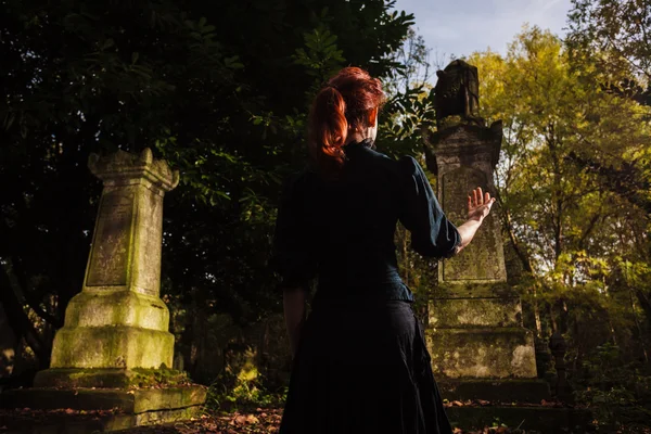 Redhead woman performing ritual at grave — Stock Photo, Image