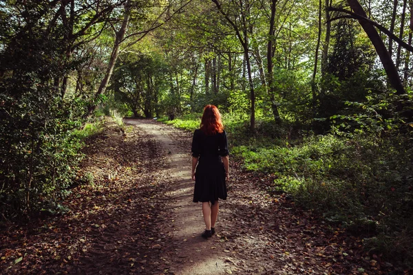 Ung kvinna promenader i skogen — Stockfoto