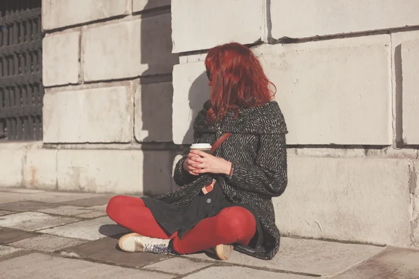 コーヒーが付いている通りに座っている若い女性 — ストック写真