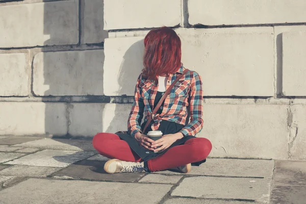 Young woman sitting in the street with coffee — Stock Photo, Image