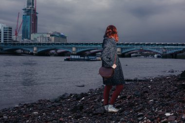 Şehirde nehir kıyısında duran genç kadın