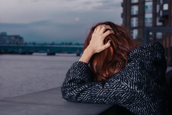 Sad woman by river in city — Stock Photo, Image