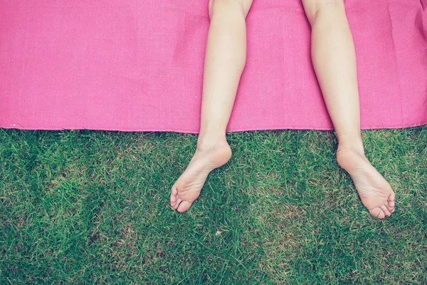 De benen van een jonge vrouw op het gras — Stockfoto