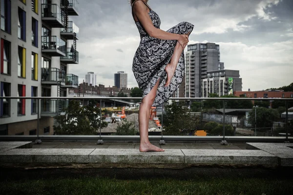 Mujer joven levantando la pierna en la azotea —  Fotos de Stock