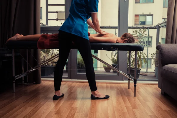 Terapeuta de massagem tratando o paciente em casa — Fotografia de Stock