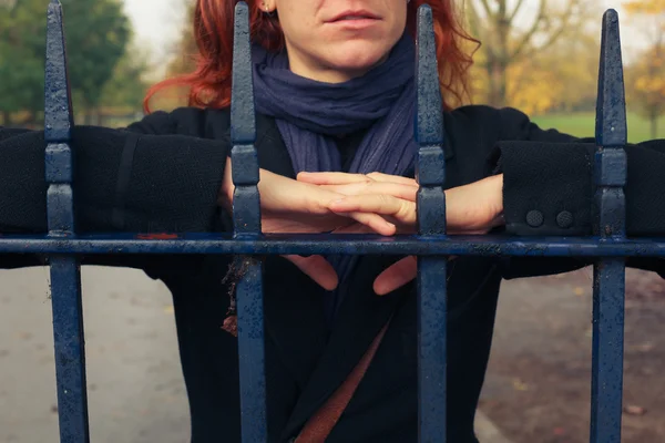 Woman leaning on gate in park — Stock Photo, Image