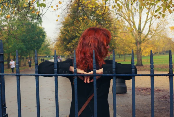 Mujer apoyada en la puerta del parque — Foto de Stock