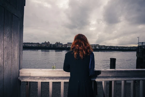 Kvinna som dricker öl vid floden — Stockfoto