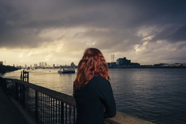 Mujer admirando la puesta de sol sobre el río en la ciudad — Foto de Stock